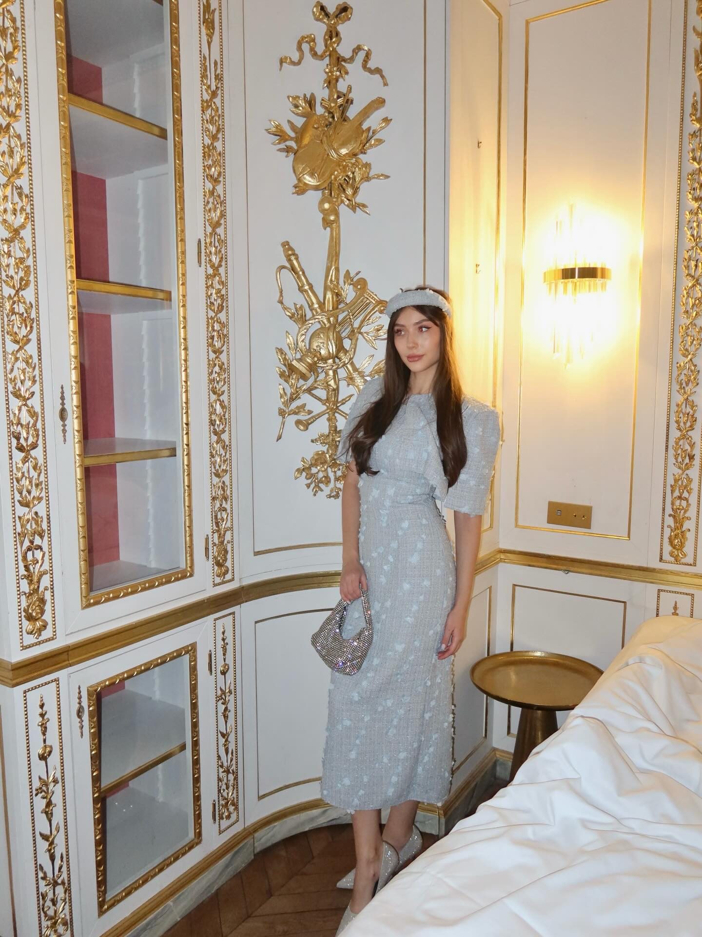 Delicia — light-blue tweed set in a gilded hotel suite, frame 2