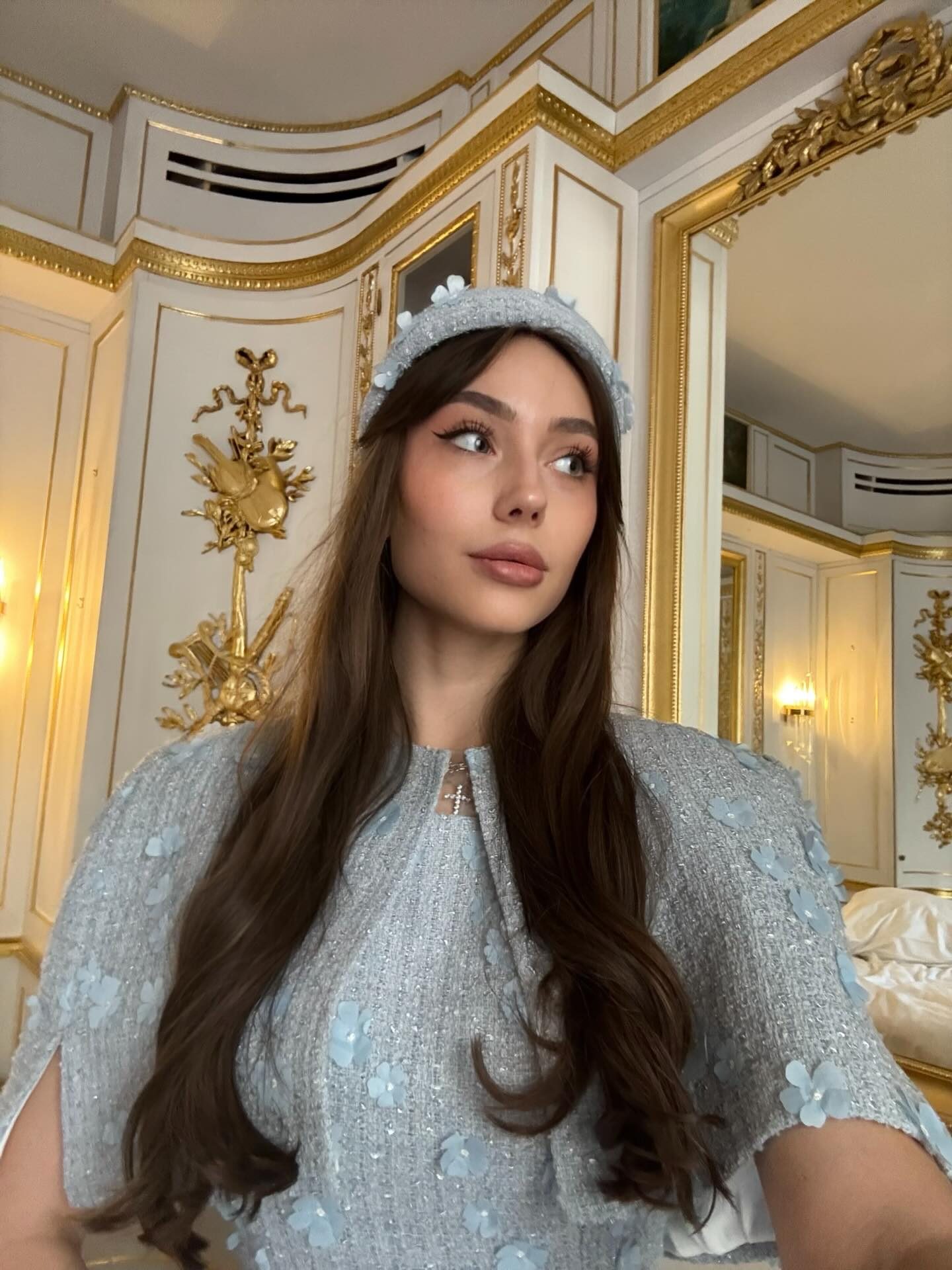 Delicia — light-blue tweed set in a gilded hotel suite, frame 3