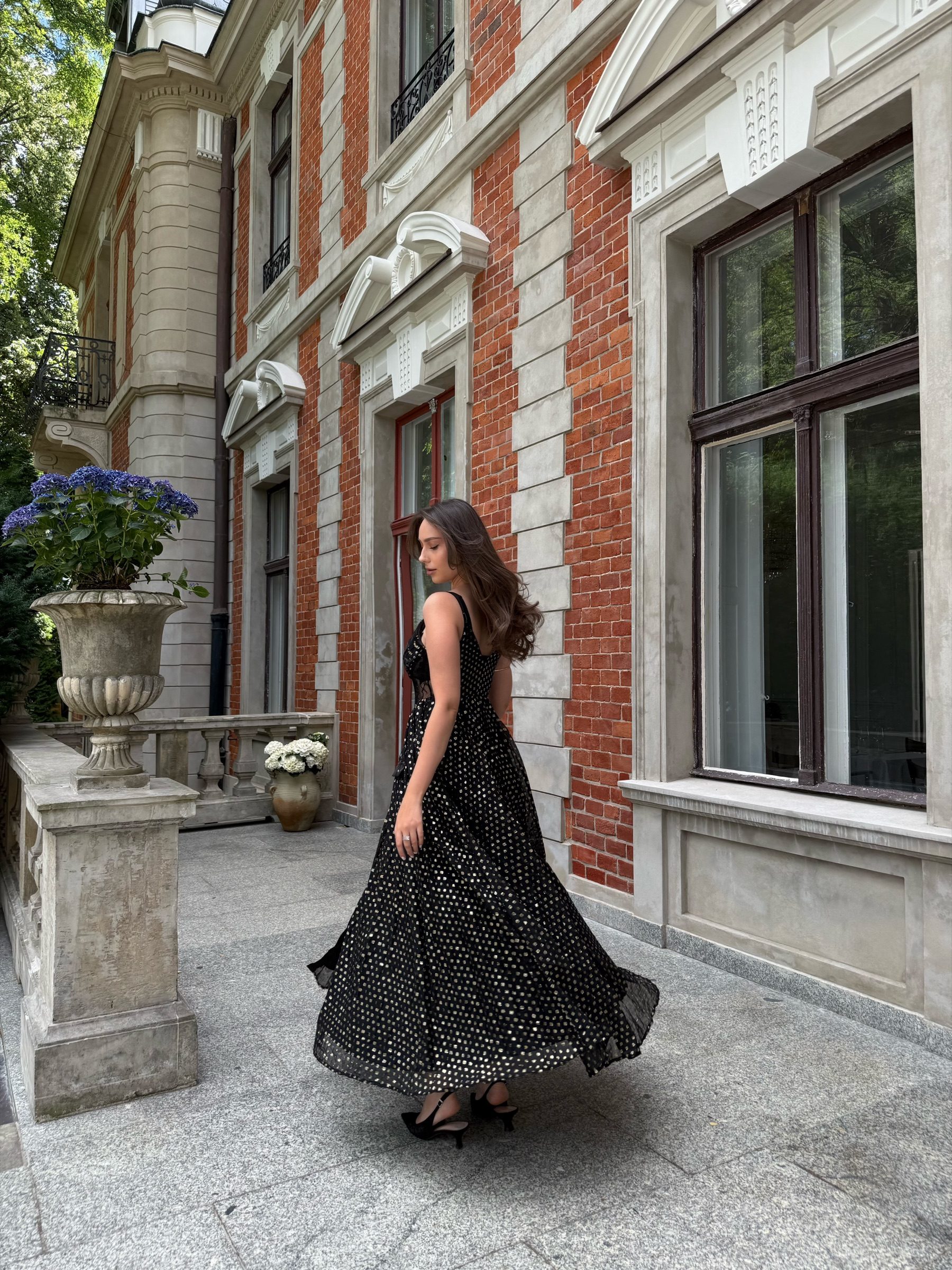Full-length editorial in a polka-dot gown, brick mansion facade